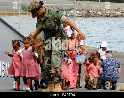 U.S. Navy Yeoman 1. Klasse Tiffany Sommer hilft Studenten aus Brain-Shapers Akademie mit hoher Geschwindigkeit Schiff (HSV) 2 Swift in Port Antonio, Jamaika, 13. Mai 2010, für eine Tour des Schiffes. Das Schiff wurde eingesetzt, südlichen Partnerschaft Station 2010, das entworfen ist, um den Informationsaustausch zwischen militärischen und zivilen Dienstleistungen im gesamten Bereich der US Southern Command der Verantwortung zu unterstützen. Stockfoto