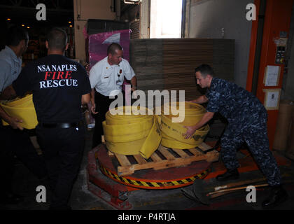 Von rechts, U.S. Navy Logistik Spezialist 2. Klasse Vitali Toptchenko; Hanz Christian, der Leitung brand Inspektor der Naval Support Activity (NSA) Neapel; und Italienischen Nationalen Feuerwehrmänner Maurazio Patrone und Alessio Storto last Brandbekämpfungsanlage auf einer Palette in Neapel, Italien, 12.08.11, 2010, für den Versand in Russland. Die russische Regierung, die dem Offiziellen angeforderte Unterstützung aus dem Departement für Verteidigung, empfängt Schutzausrüstung Brandbekämpfung Ausrüstung und anderen Tools laufenden wildfires im Land zu bekämpfen. (DoD Stockfoto