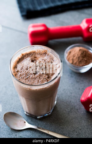 Protein Shake Schokolade Smoothie mit Whey Protein Pulver und roten Hanteln. Sports Drink Stockfoto