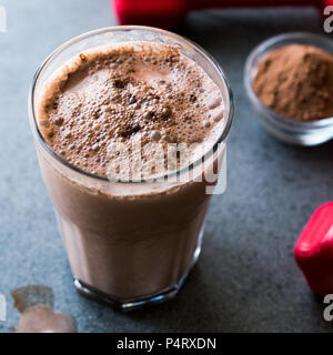 Protein Shake Schokolade Smoothie mit Whey Protein Pulver und roten Hanteln. Sports Drink Stockfoto