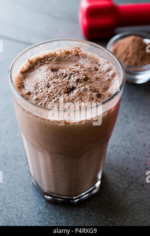 Protein Shake Schokolade Smoothie mit Whey Protein Pulver und roten Hanteln. Sports Drink Stockfoto