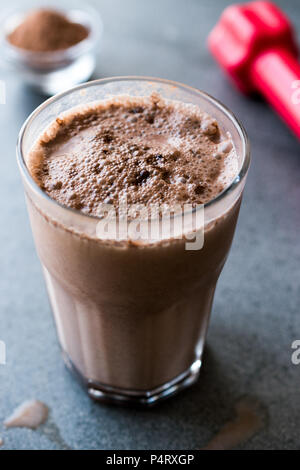 Protein Shake Schokolade Smoothie mit Whey Protein Pulver und roten Hanteln. Sports Drink Stockfoto