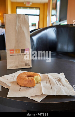 Beutel mit Donuts oder Krapfen mit einer Ebene ganz oder teilweise gegessen Donut auf eine Serviette bei Dunkin Donuts Laden oder Speichern in Montgomery Alabama, USA. Stockfoto