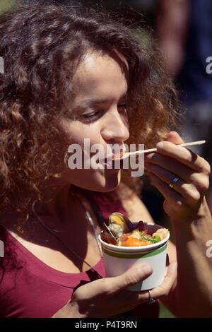 Frau essen Essen aus einem Pappbecher mit Genuss am BC Seafood Festival in Comox, Kanada 2018 Stockfoto