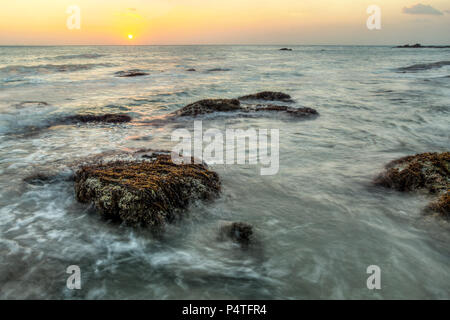 Lange Belichtung geschossen von Gesteinen mit Algen und Seegras nicht durch das Meer bei Ebbe fallen, im Abendlicht. Koh Lanta, Thailand Stockfoto