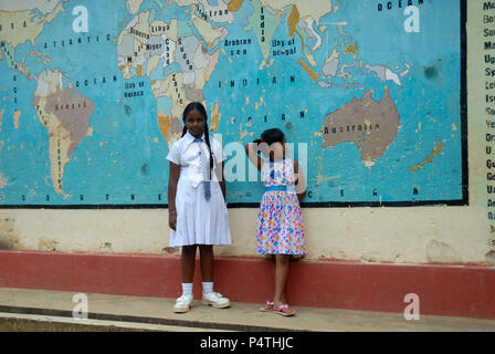 Zwei Schulmädchen, die sich eine Karte ansehen, die an der Wand der Schule gemalt ist, Lankathilaka Maha Vidyalaya, Kovilakanda, Sri Lanka. Stockfoto