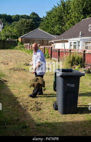 Alte Mann bis harken Gras nach der Rasen ist gemäht worden. Stockfoto