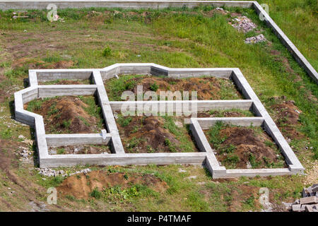 Baustelle im grünen Bereich. Gräben gegraben und mit Zement als Grundlage für das zukünftige Haus und Zaun um Territorium gefüllt. Gebäude, konst Stockfoto