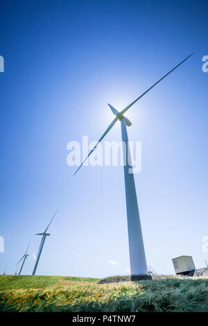 Eine Serie von drei Windkraftanlagen in einer Windmühle Park gegen ein strahlend blauer Himmel. Stockfoto