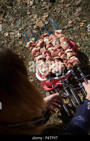 Frau hält saftig und lecker Schweinefleisch Kebab am Spieß. Grill Party Konzept. Der frühe Frühling Tag. Ansicht von oben. Stockfoto