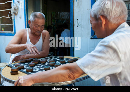 Dunhuang, China - 7. August 2012: Zwei chinesische Mann spielen chinesische Schach (Xiangqi) in einer Straße von der Stadt Dunhuang, China Stockfoto