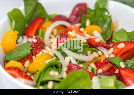 Sommer fruchtig Bio Spinat Salat mit Mandarin, Strrawberry, Zwiebeln und Pinienkernen Stockfoto