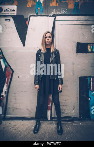 Portrait von ernsthaften jungen Frau in Schwarz stand vor der Graffiti gekleidet Stockfoto