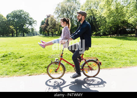 Gerne Vater Reiten Fahrrad mit Tochter sitzen auf Lenker in einem Park Stockfoto