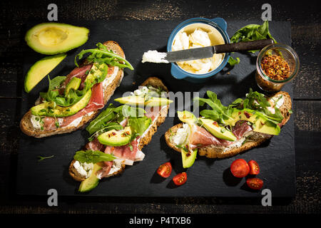 Zwiebel Brot mit Frischkäse, Parma Schinken, Avocado, Rucola, Thymian und Tomaten Stockfoto