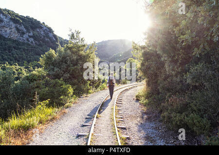 Griechenland, Pilion, Milies, Rückansicht des Menschen zu Fuß entlang der Schienen der Schmalspurbahn Stockfoto