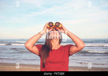 Frau mit Fernglas am Strand Stockfoto