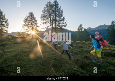 Familie Wandern in alpiner Wiese bei Sonnenuntergang Stockfoto