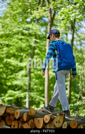 Junge mit Rucksack Balancieren auf Logs im Wald Stockfoto