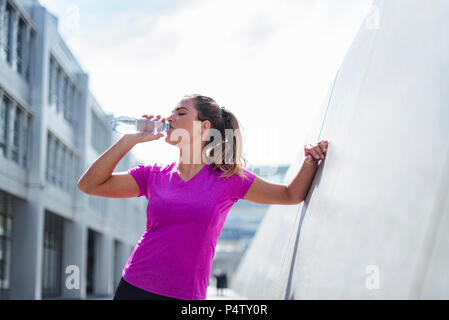 Junge Frau mit einer Unterbrechung von der Ausübung von Trinken aus der Flasche Stockfoto