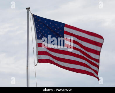 United Flaggenstaaten winken auf einer Stange mit Wolken hinter Stockfoto