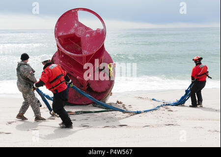 Sgt. 1. Klasse Chris Richards der Connecticut National Guard zusammen mit der U.S. Coast Guard Chief Warrant Officer Benjamin Jewell, und Petty Officer 3rd Class Andrew Hayden der Coast Guard Cutter Eiche bereiten den Riemen, wird verwendet, um eine 12.000-Pound Strände Boje zu Hoist, Dienstag, 9. Mai 2017, in der Nähe von Chatham, Massachusetts. Die Boje brach aus der Verankerung an der Küste von Maine während ein Wintersturm an Land gespült und schließlich in der Nähe von Chatham. Stockfoto