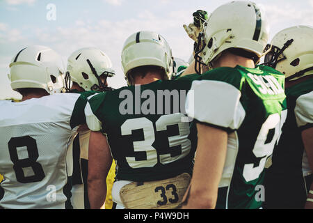 Gruppe junger American Football Spieler gemeinsam mit ihren Waffen in einer Unordnung vor einem Spiel Stockfoto