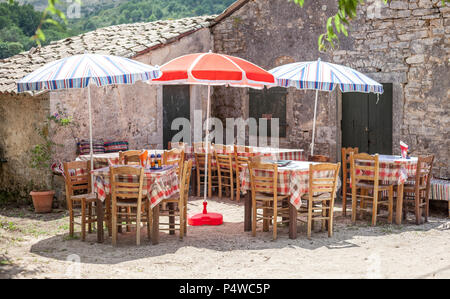 Bunte Sonnenschirme für den Esstisch. Schachbrettmuster tuchbelag das Holz. Unbebautes Grundstück mit Speisen für die Kunden. Land restauran Stockfoto