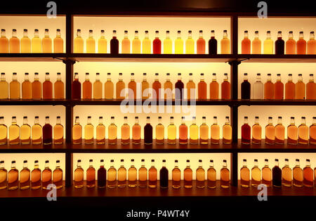 Unmarkierte Glas Whiskey Flaschen auf beleuchteten Regale angezeigt Stockfoto