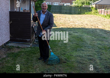 Alte Mann bis harken Gras nach der Rasen ist gemäht worden. Stockfoto