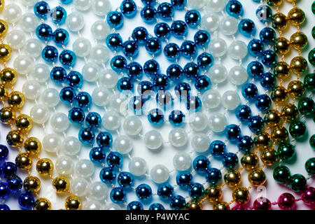 Makro Zusammenfassung Hintergrund mit bunten Mardi Gras Perlenketten zufällig auf eine weiße Fläche angeordnet Stockfoto