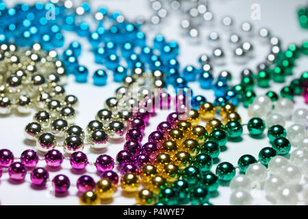 Makro Zusammenfassung Hintergrund mit bunten Mardi Gras Perlenketten zufällig auf eine weiße Fläche angeordnet Stockfoto