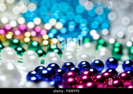 Makro Zusammenfassung Hintergrund mit bunten Mardi Gras Perlenketten zufällig auf eine weiße Fläche angeordnet Stockfoto