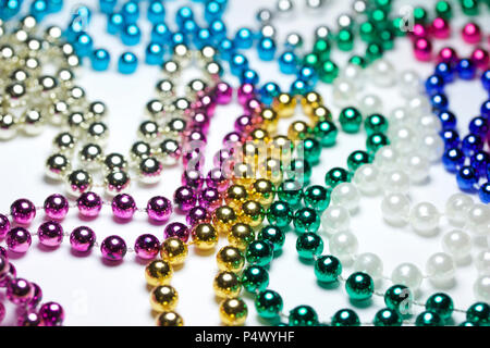 Makro Zusammenfassung Hintergrund mit bunten Mardi Gras Perlenketten zufällig auf eine weiße Fläche angeordnet Stockfoto