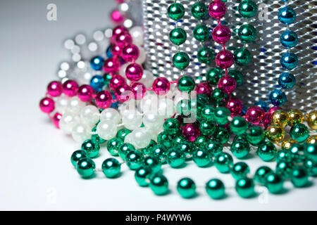 Makro Zusammenfassung Hintergrund mit bunten Mardi Gras Perlenketten zufällig auf eine weiße Fläche angeordnet Stockfoto