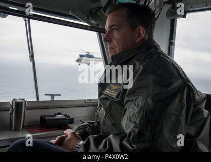 Gewässer südlich von Japan (10. Mai 2017) Kapitän Buzz Donnelly, kommandierender Offizier der Vorwärts bereitgestellt Flugzeugträger der Marine, USS Ronald Reagan (CVN 76), beobachtet den Flugbetrieb von der Kommandobrücke während einer vertikalen Auffüllung-auf-See. SA-330 J Pumas, militärische Sealift Command Dry Cargo und Munition Schiff zugewiesen, USNS Charles Drew (T-AKE 10), übertragen Ordnance zu Ronald Reagan's Flight Deck. Ronald Reagan, das Flaggschiff der Carrier Strike Group 5, bietet eine Bekämpfung bereit, Kraft, schützt und verteidigt die kollektive maritime Interessen seiner Verbündeten und Partnern in der Indo-As Stockfoto