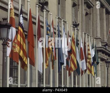 BANDERAS AUTONOMICAS EN LA FACHADA DEL PALACIO DEL SENADO DE LA PLAZA DE LA MARINA ESPAÑOLA. Lage: SENADO - AUSSEN, MADRID, SPANIEN. Stockfoto