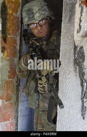 Ein Soldat der US-Armee, zu multinationalen Battle Group-East's Forward Command Post zugeordnet, löscht ein Gebäude neben seinem platoon während einer Übung in Gracanica, Kosovo, Mai 10. Beginnend mit einem Eindringen von Luft, die Soldaten durchgeführt demontiert Aufklärung über die Gegend und die Kontrolle von einem verlassenen Dorf. Stockfoto