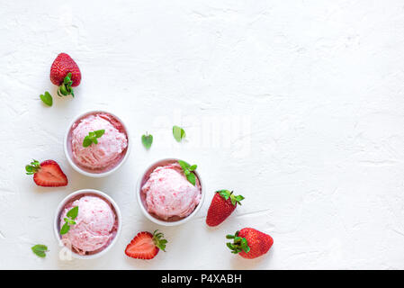 Erdbeereis und frische Erdbeeren auf weißem Hintergrund, Ansicht von oben. Drei Becher Erdbeereis, gesunden Sommer Nachtisch. Stockfoto