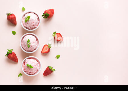 Erdbeereis und frische Erdbeeren auf rosa Hintergrund, Ansicht von oben. Drei Becher Erdbeereis, gesunden Sommer Nachtisch. Stockfoto