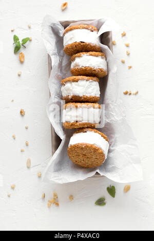 Eis-Sandwiches mit Muttern und Vollkorn Cookies. Hausgemachtes Vanilleeis Sandwiches auf weißem Hintergrund. Stockfoto