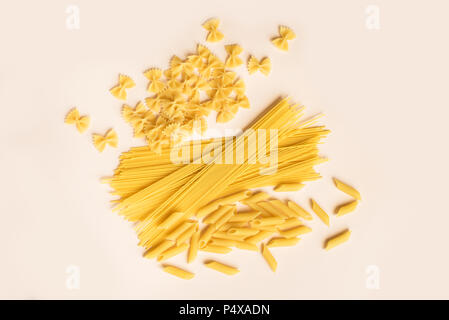 Verschiedene verschiedene Roh rohe Nudeln auf Rosa pastell Hintergrund. Italienische Pasta: Penne, Farfalle, Spaghetti. Stockfoto