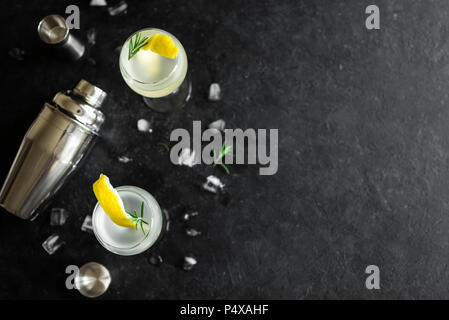 Alkohol Cocktail mit Zitrone, Rosmarin und Eis. Gin Tonic fizz oder gimlet Cocktail auf schwarzen Hintergrund, kopieren. Stockfoto