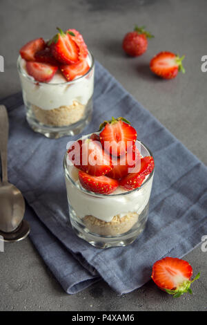 Strawberry trifle Mini Dessert in Gläsern mit frischen Erdbeeren und Sahne Käse auf grauem Beton Hintergrund. Gesunde hausgemachte potrion Dessert. Stockfoto