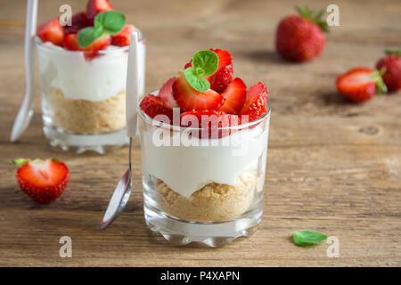 Strawberry trifle Mini Dessert in Gläsern mit frischen Erdbeeren und Sahne Käse auf Holz- Hintergrund. Gesunde hausgemachte potrion Dessert. Stockfoto