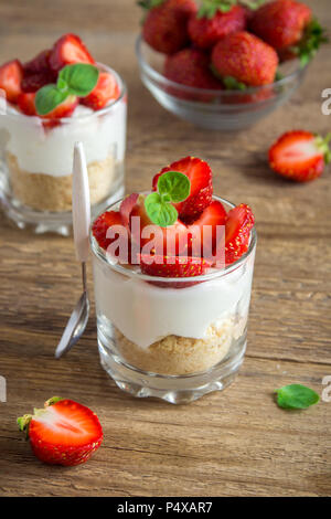 Strawberry trifle Mini Dessert in Gläsern mit frischen Erdbeeren und Sahne Käse auf Holz- Hintergrund. Gesunde hausgemachte potrion Dessert. Stockfoto