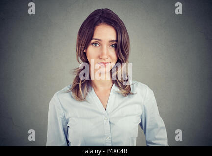 Skeptisch verdächtige Junge business Frau an der Kamera auf grauen Hintergrund suchen Stockfoto