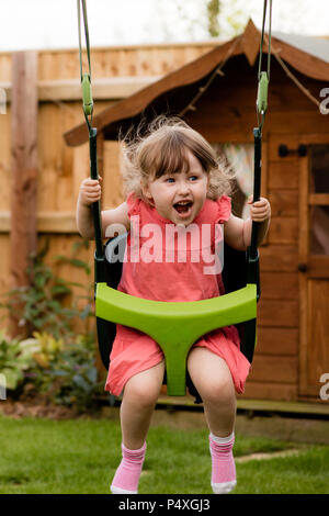 Eine gespenstische Mädchen lachen während des Spielens auf der Schaukel Stockfoto