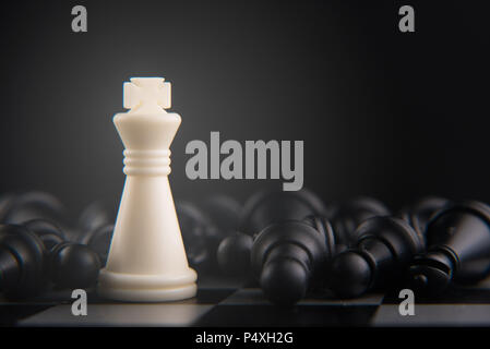 Schach auf Schachbrett. weiße König besiegt Alle. Macht, Helden und Leadership Konzept. Weich und selektiven Fokus Stockfoto