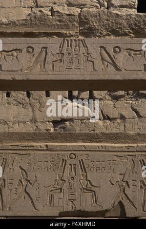 Relief zeigt Gott Amun mit toller Helm mit zwei großen Federn und Bart sitzt auf dem Thron. Ersten Hof des Ramses II. Neuen Imperiums. Tempel von Luxor. Ägypten. Stockfoto